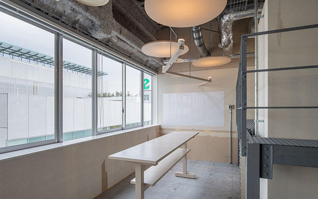MUSASHi Innovation Lab CLUEの内観。窓際にテーブルと椅子が並ぶワークスペース
